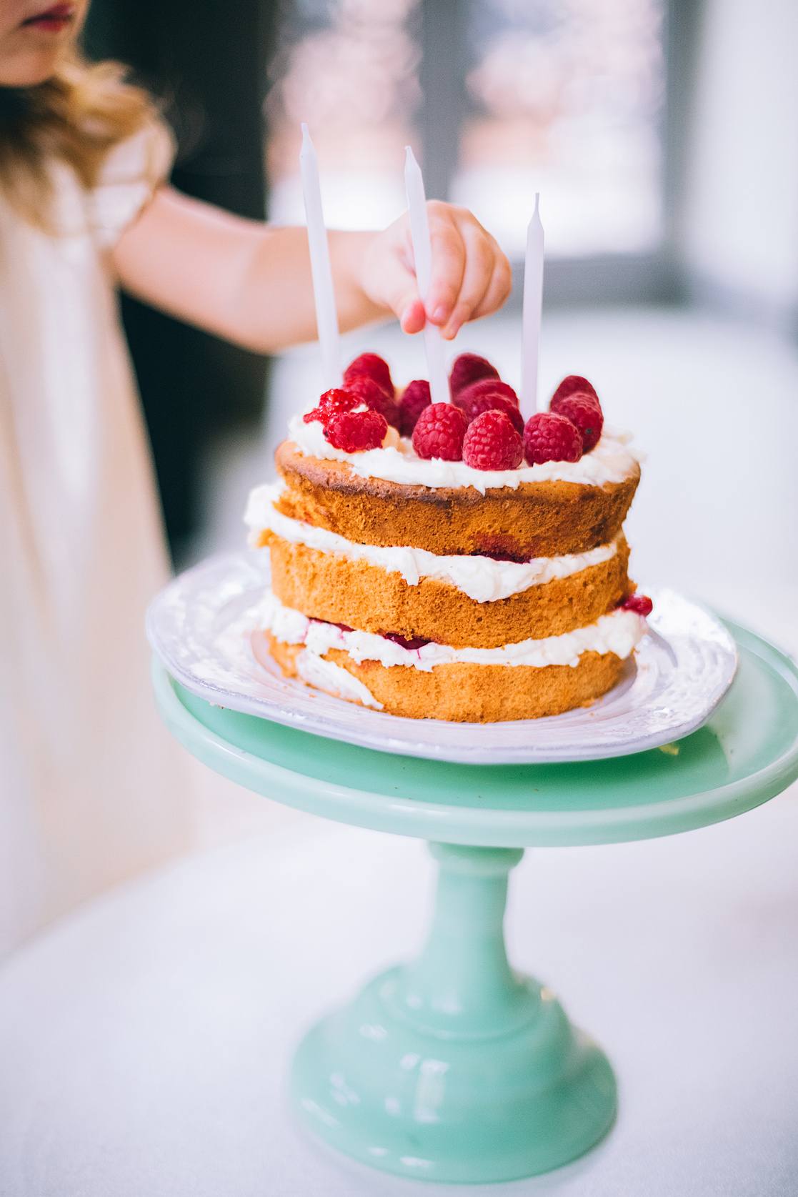 Girl Putting a Candle on 3-layered Cake